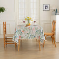 Elegant floral tablecloth with lush green leaves and soft pastel blossoms, accented by delicate tassel edging — perfect for adding a fresh, nature-inspired touch to dining rooms, garden parties, or spring gatherings.