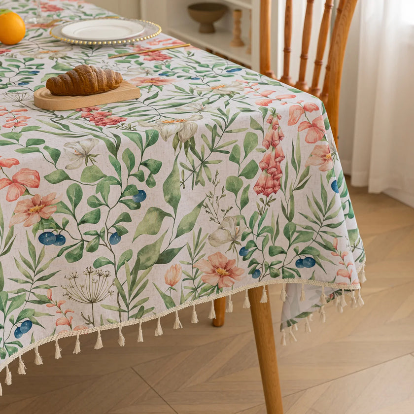 Elegant floral tablecloth with lush green leaves and soft pastel blossoms, accented by delicate tassel edging ¡ª perfect for adding a fresh, nature-inspired touch to dining rooms, garden parties, or spring gatherings.