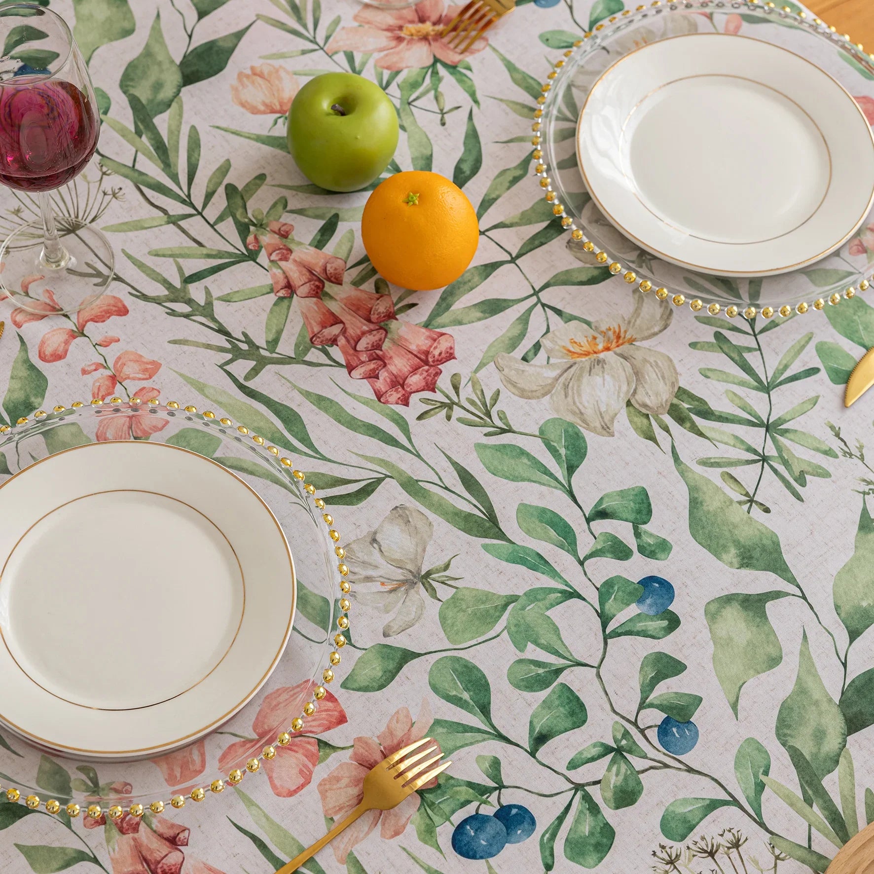Elegant floral tablecloth with lush green leaves and soft pastel blossoms, accented by delicate tassel edging — perfect for adding a fresh, nature-inspired touch to dining rooms, garden parties, or spring gatherings.