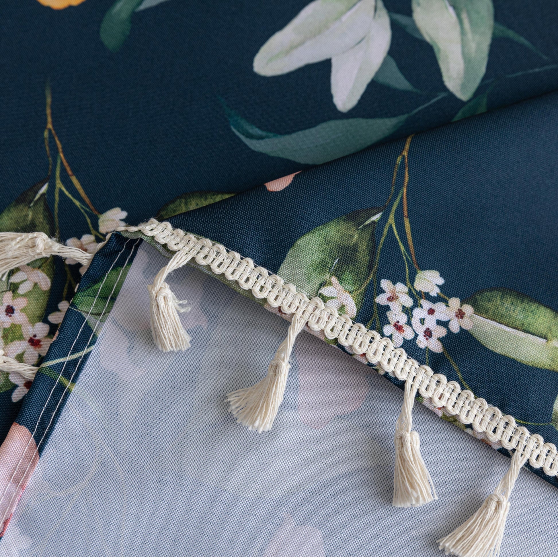Chic dark floral tablecloth featuring vibrant botanical prints on a deep navy background, finished with elegant tassel edges — ideal for elevating dining décor, special occasions, and stylish everyday meals.