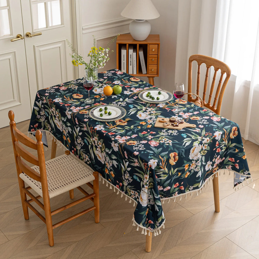 Chic dark floral tablecloth featuring vibrant botanical prints on a deep navy background, finished with elegant tassel edges — ideal for elevating dining décor, special occasions, and stylish everyday meals.