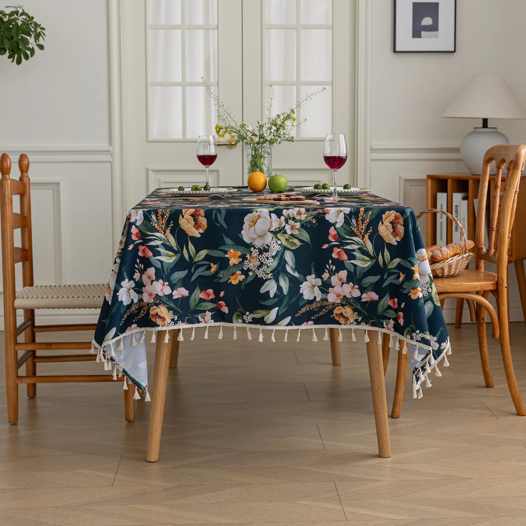 Chic dark floral tablecloth featuring vibrant botanical prints on a deep navy background, finished with elegant tassel edges — ideal for elevating dining décor, special occasions, and stylish everyday meals.