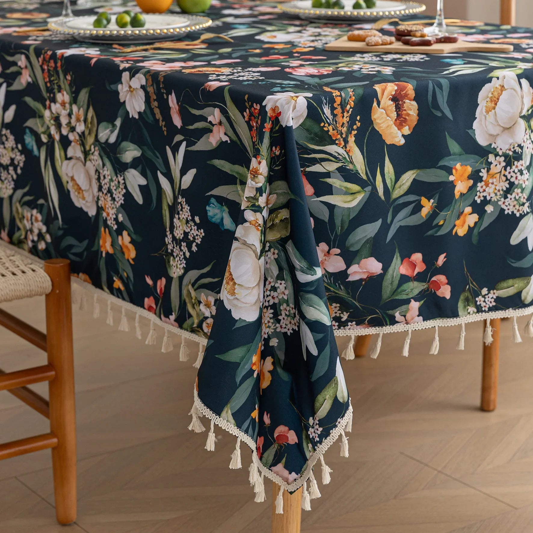 Chic dark floral tablecloth featuring vibrant botanical prints on a deep navy background, finished with elegant tassel edges — ideal for elevating dining décor, special occasions, and stylish everyday meals.