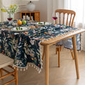 Chic dark floral tablecloth featuring vibrant botanical prints on a deep navy background, finished with elegant tassel edges — ideal for elevating dining décor, special occasions, and stylish everyday meals.