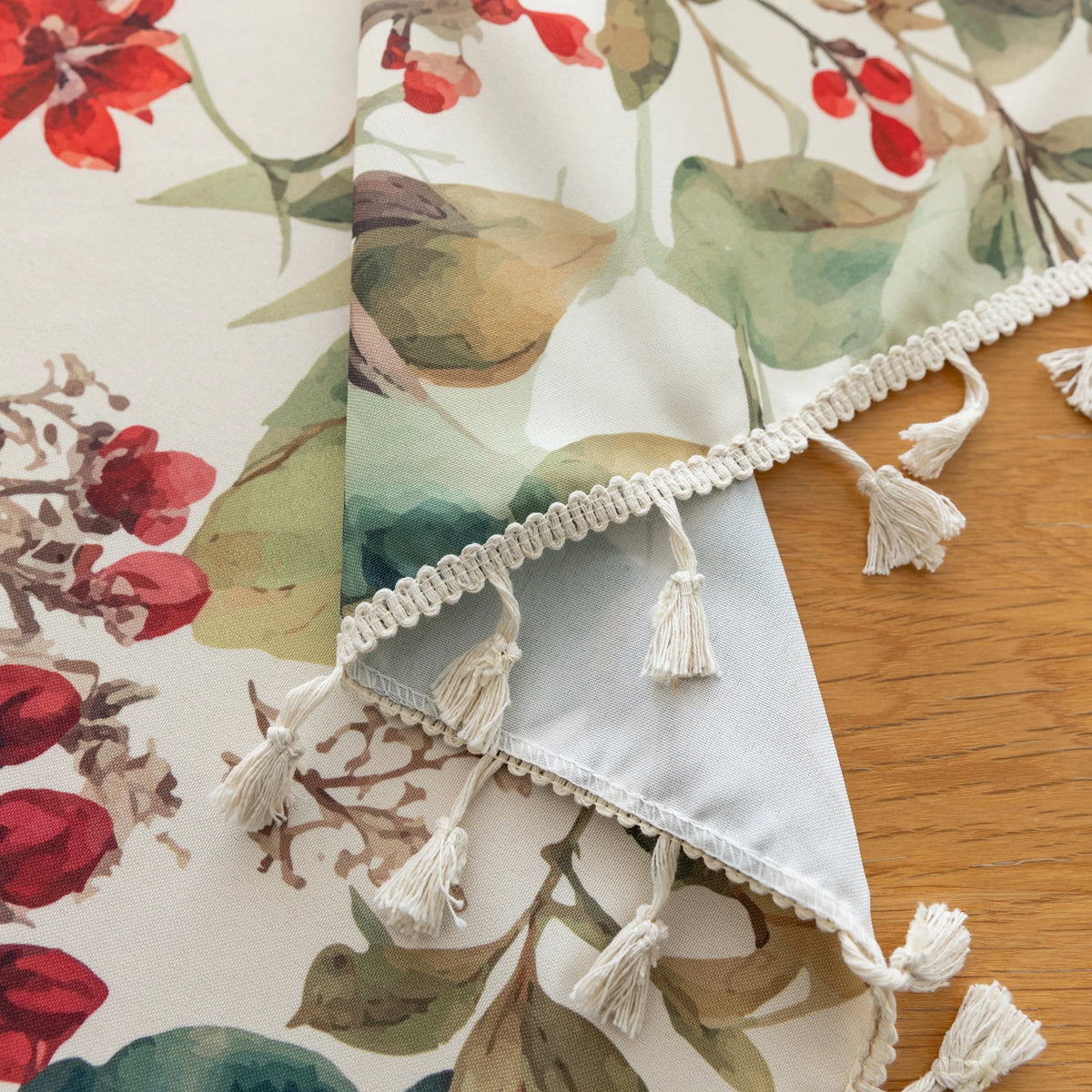 Beautiful floral tablecloth with vibrant red, green, and beige botanical patterns, enhanced by delicate tassel edging ¡ª perfect for adding a warm, inviting touch to everyday dining or festive gatherings.