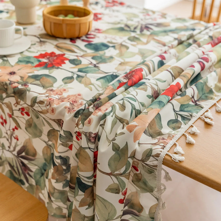 Beautiful floral tablecloth with vibrant red, green, and beige botanical patterns, enhanced by delicate tassel edging ¡ª perfect for adding a warm, inviting touch to everyday dining or festive gatherings.