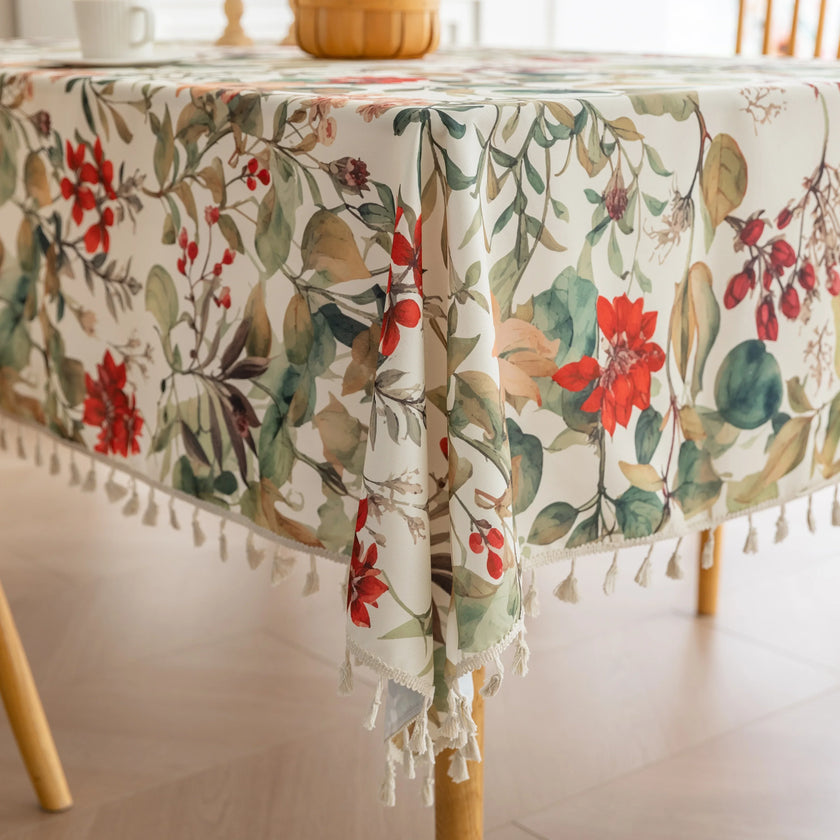 Beautiful floral tablecloth with vibrant red, green, and beige botanical patterns, enhanced by delicate tassel edging ¡ª perfect for adding a warm, inviting touch to everyday dining or festive gatherings.