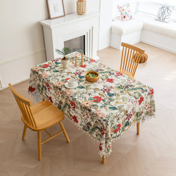 Beautiful floral tablecloth with vibrant red, green, and beige botanical patterns, enhanced by delicate tassel edging — perfect for adding a warm, inviting touch to everyday dining or festive gatherings.