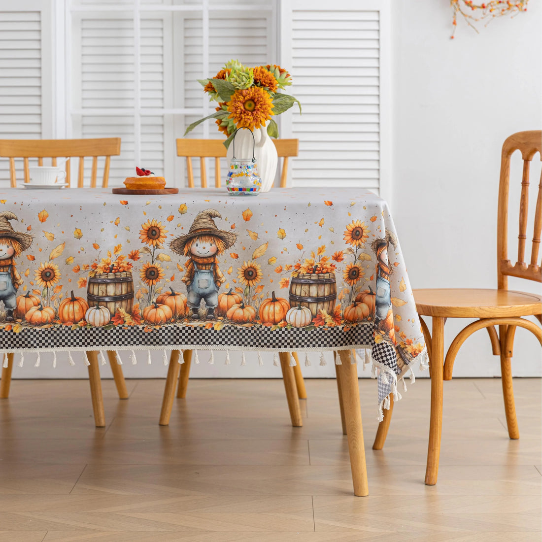 Autumn Harvest Rectangular Tablecloth – Add seasonal charm to your dining space with this festive rectangular tablecloth featuring a delightful harvest design of pumpkins, sunflowers, wooden barrels, and a friendly scarecrow. Accented with a black-and-white checkered border and finished with cream tassels, it brings a cozy farmhouse feel to your table. Perfect for fall gatherings, Thanksgiving dinners, and rustic home décor, this durable and vibrant tablecloth enhances any seasonal celebration.
