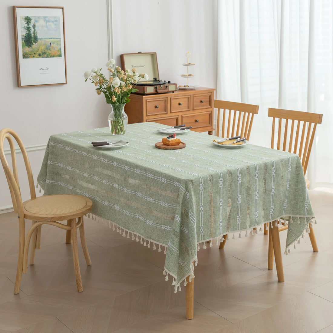 Light green woven tablecloth with white geometric stripe patterns and decorative tassel edges.