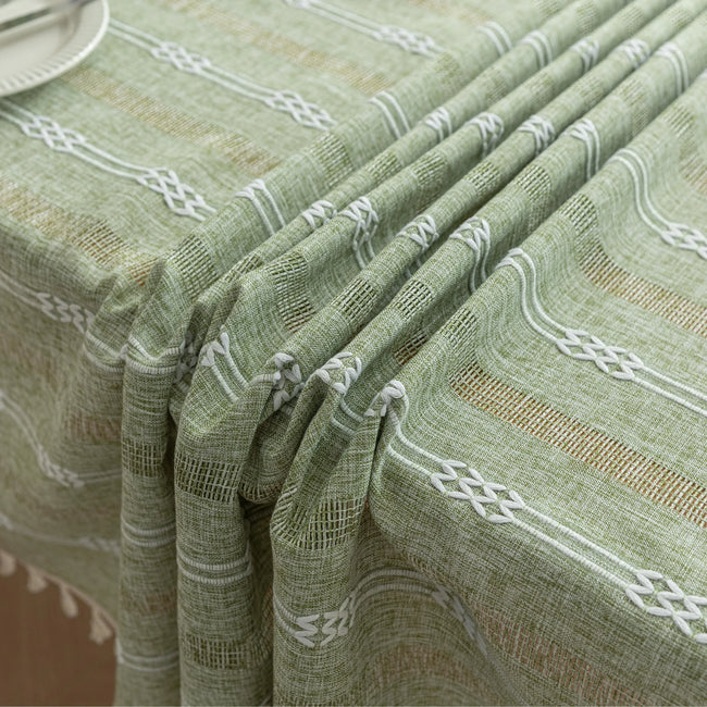 Light green woven tablecloth with white geometric stripe patterns and decorative tassel edges.