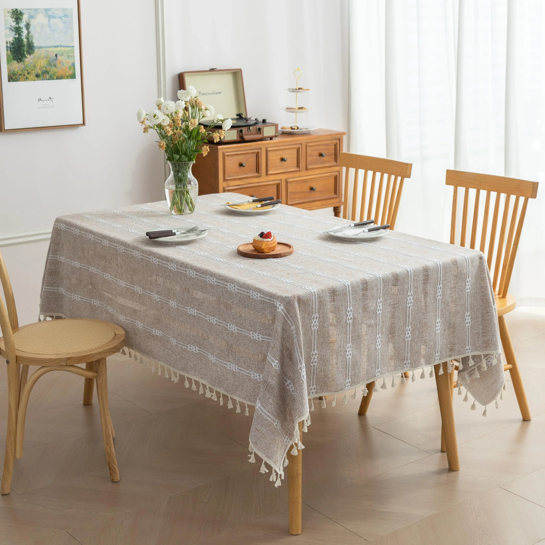 Rustic Linen Tassel Tablecloth – Add a touch of natural elegance to your dining space with this beautiful linen-blend tablecloth, featuring delicate white embroidered stripes and charming tassel edging. Its neutral beige tone effortlessly complements farmhouse, bohemian, and modern interiors, making it perfect for everyday meals or special gatherings. Durable, soft, and easy to clean, this tablecloth not only protects your table but also enhances your dining experience with timeless style and texture.
