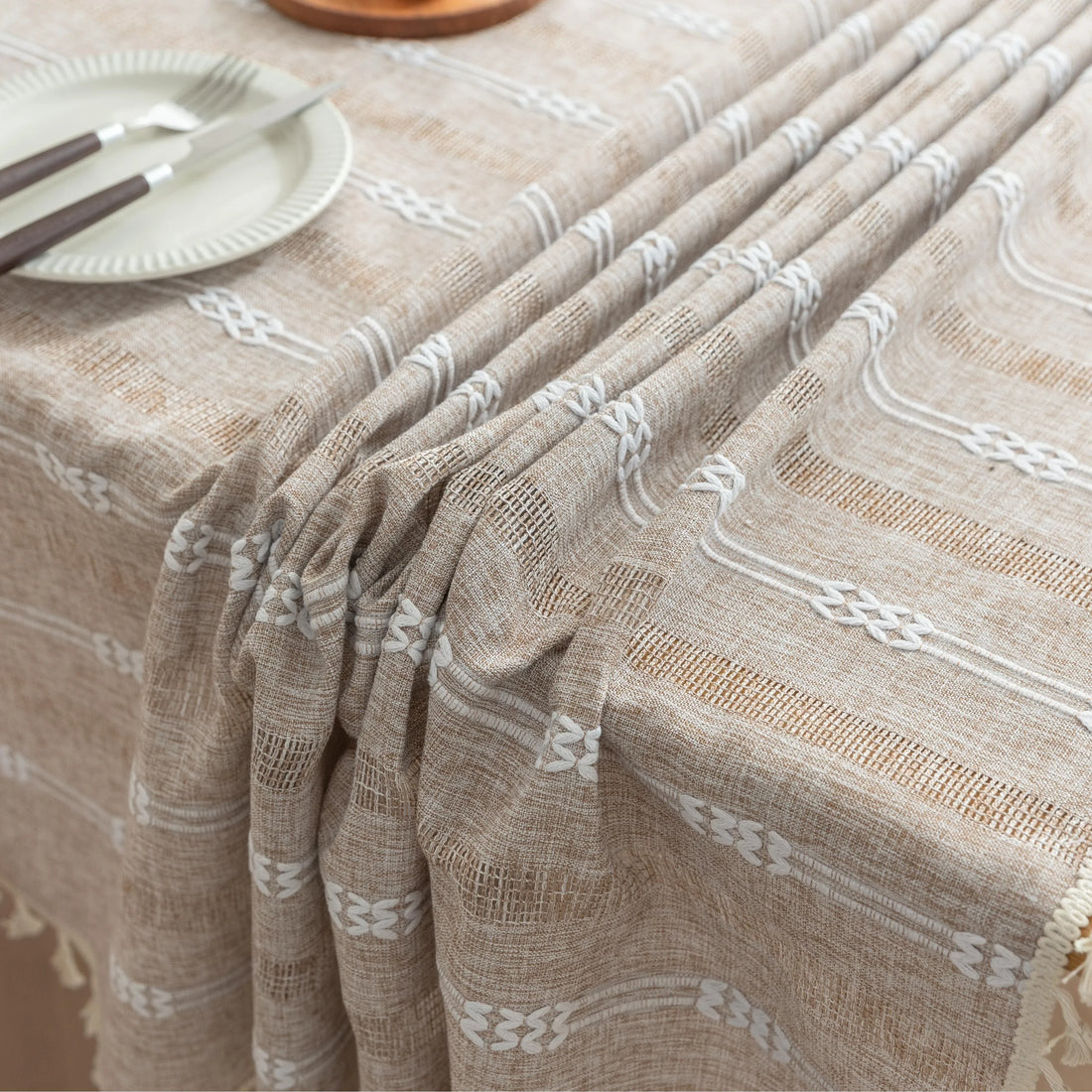 Rustic Linen Tassel Tablecloth – Add a touch of natural elegance to your dining space with this beautiful linen-blend tablecloth, featuring delicate white embroidered stripes and charming tassel edging. Its neutral beige tone effortlessly complements farmhouse, bohemian, and modern interiors, making it perfect for everyday meals or special gatherings. Durable, soft, and easy to clean, this tablecloth not only protects your table but also enhances your dining experience with timeless style and texture.
