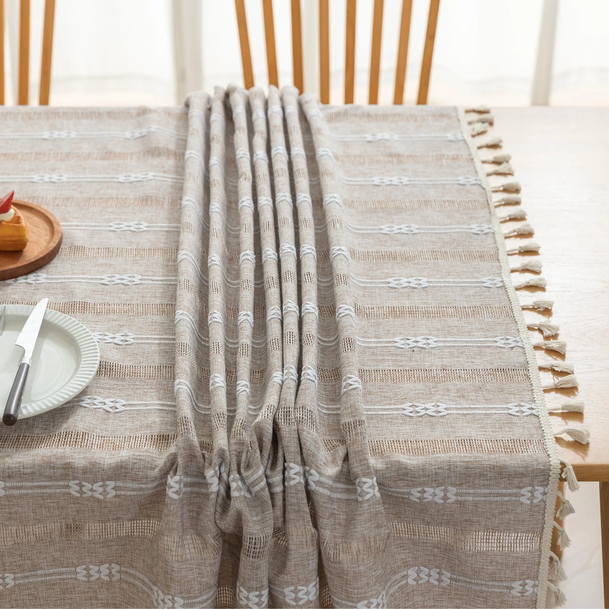 Rustic Linen Tassel Tablecloth – Add a touch of natural elegance to your dining space with this beautiful linen-blend tablecloth, featuring delicate white embroidered stripes and charming tassel edging. Its neutral beige tone effortlessly complements farmhouse, bohemian, and modern interiors, making it perfect for everyday meals or special gatherings. Durable, soft, and easy to clean, this tablecloth not only protects your table but also enhances your dining experience with timeless style and texture.
