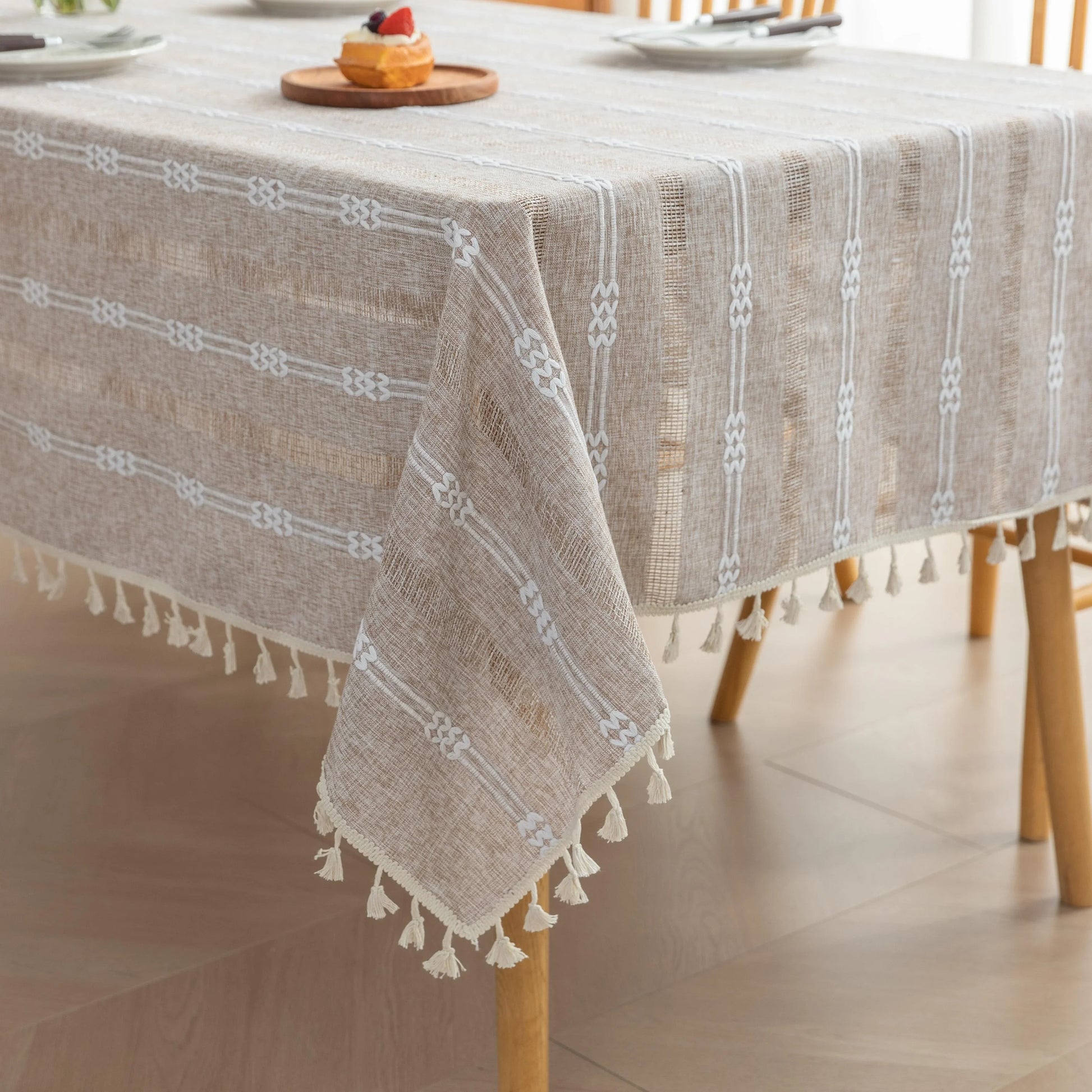 Rustic Linen Tassel Tablecloth – Add a touch of natural elegance to your dining space with this beautiful linen-blend tablecloth, featuring delicate white embroidered stripes and charming tassel edging. Its neutral beige tone effortlessly complements farmhouse, bohemian, and modern interiors, making it perfect for everyday meals or special gatherings. Durable, soft, and easy to clean, this tablecloth not only protects your table but also enhances your dining experience with timeless style and texture.
