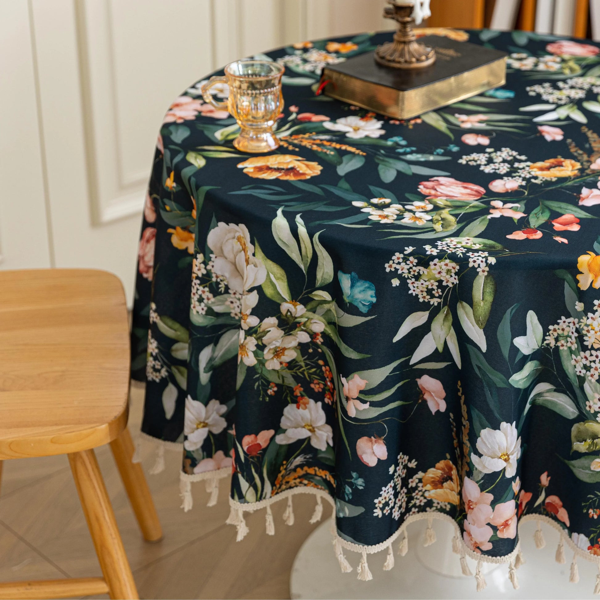 Elegant Dark Floral Round Tablecloth – Add a touch of sophistication to your dining area with this round tablecloth featuring a rich dark green background adorned with vibrant floral prints in shades of orange, pink, and white. Finished with delicate white tassels, it combines elegance with charm, making it perfect for everyday meals, tea parties, or special gatherings. Durable and stylish, it complements both modern and classic home décor.
