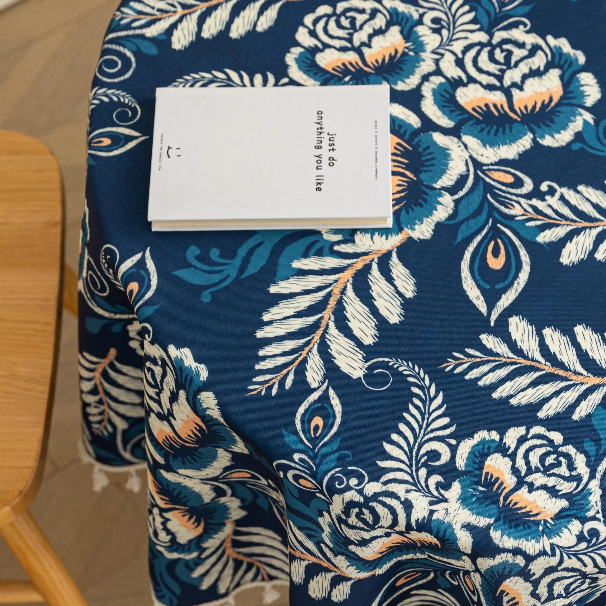 Elegant Floral Round Tablecloth – Enhance your dining space with this stylish round tablecloth featuring a deep navy blue background adorned with delicate white and beige floral patterns. Accented with charming white tassels along the edge, it brings a refined yet cozy touch to your table décor. Perfect for everyday meals, afternoon tea, or special gatherings, this durable and decorative tablecloth suits both modern and classic interiors.
