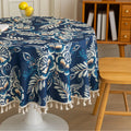 Elegant Floral Round Tablecloth – Enhance your dining space with this stylish round tablecloth featuring a deep navy blue background adorned with delicate white and beige floral patterns. Accented with charming white tassels along the edge, it brings a refined yet cozy touch to your table décor. Perfect for everyday meals, afternoon tea, or special gatherings, this durable and decorative tablecloth suits both modern and classic interiors.
