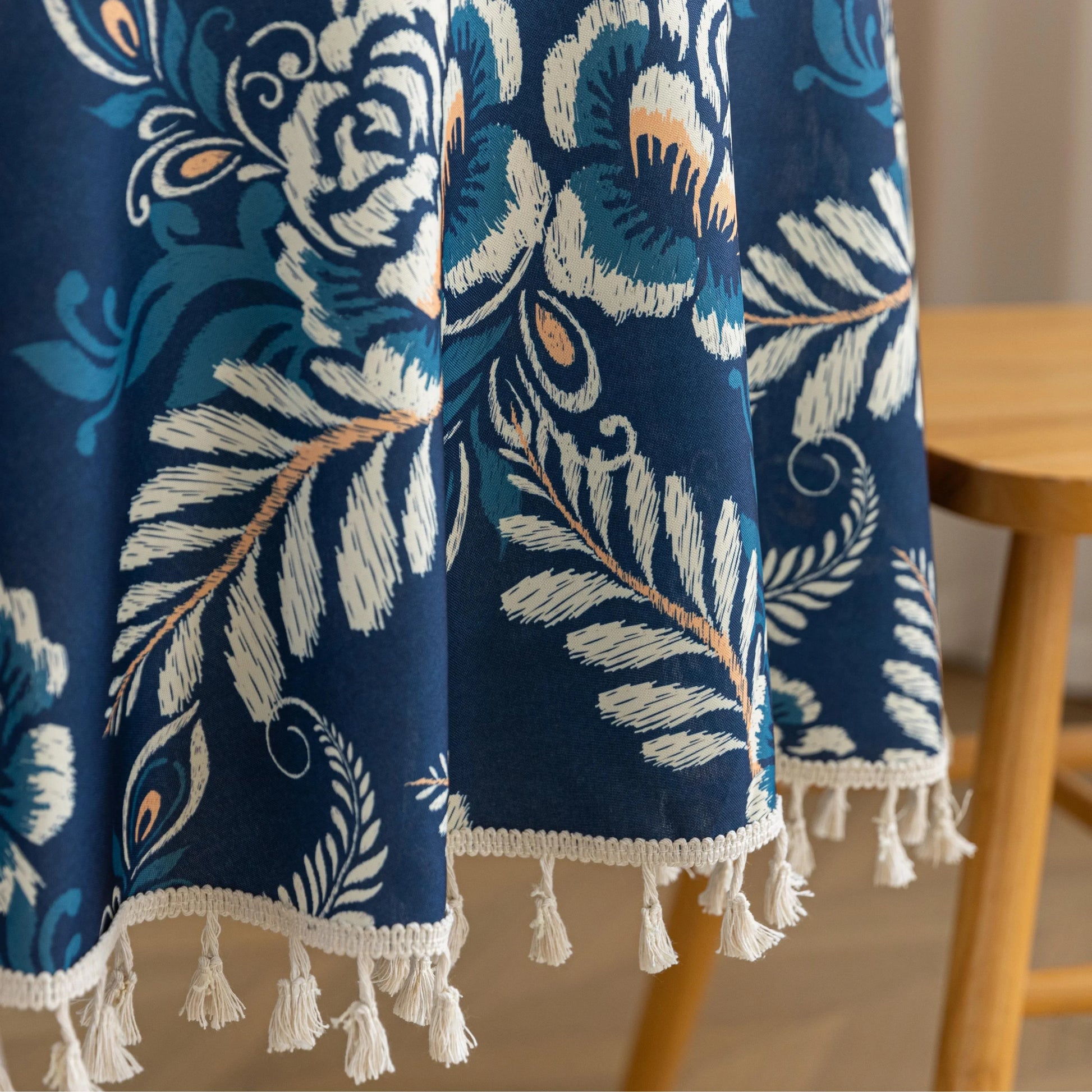 Elegant Floral Round Tablecloth – Enhance your dining space with this stylish round tablecloth featuring a deep navy blue background adorned with delicate white and beige floral patterns. Accented with charming white tassels along the edge, it brings a refined yet cozy touch to your table décor. Perfect for everyday meals, afternoon tea, or special gatherings, this durable and decorative tablecloth suits both modern and classic interiors.
