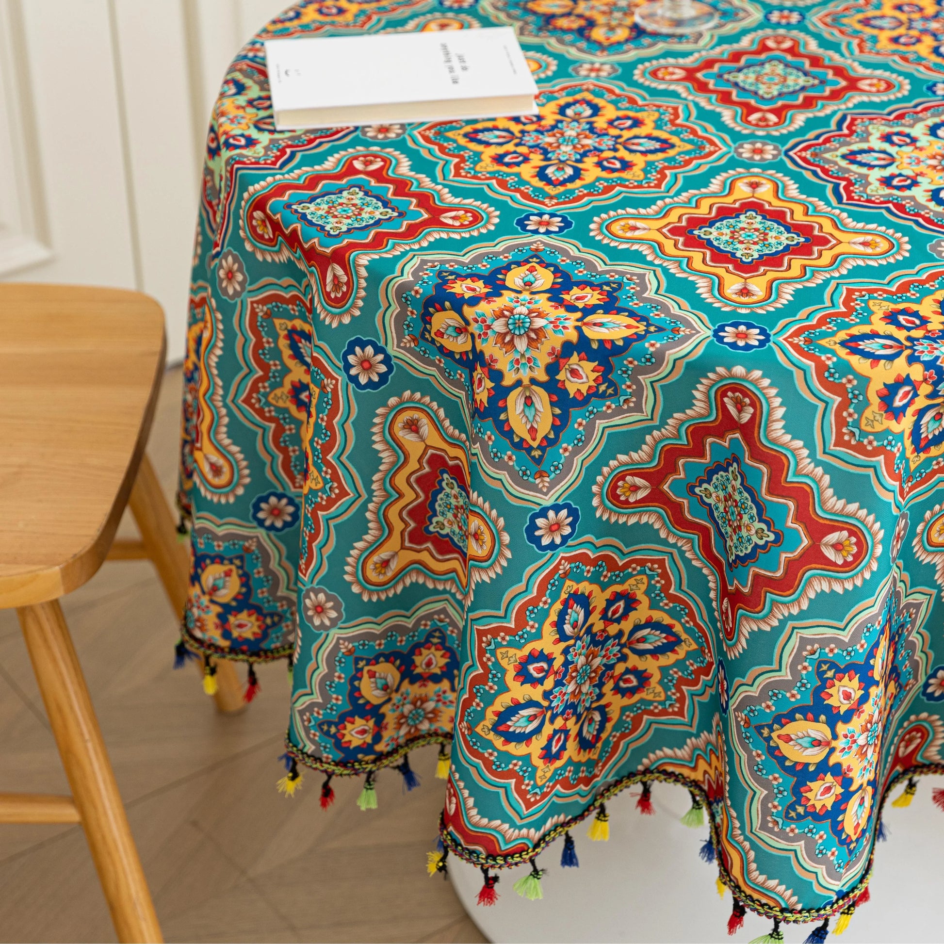 Bohemian Round Tablecloth – Add vibrant charm to your dining area with this colorful round tablecloth featuring intricate Moroccan-inspired patterns in bold turquoise, red, and yellow hues. Finished with playful multicolor tassels along the edge, it brings a lively boho flair to both indoor and outdoor dining. Perfect for kitchen tables, coffee nooks, or garden parties, this durable and eye-catching tablecloth is ideal for everyday use or special occasions.

