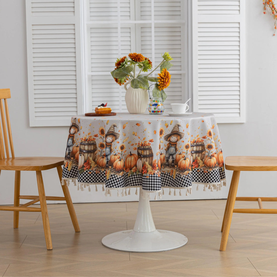 Autumn Harvest Round Tablecloth – Celebrate the cozy season with this charming round tablecloth featuring a delightful harvest design of pumpkins, sunflowers, barrels, and scarecrows. Accented with a black-and-white checkered border and finished with cream tassels, it brings a warm, festive touch to your dining space. Perfect for fall gatherings, Thanksgiving dinners, or seasonal décor, this durable and vibrant tablecloth adds rustic charm to any table setting.
