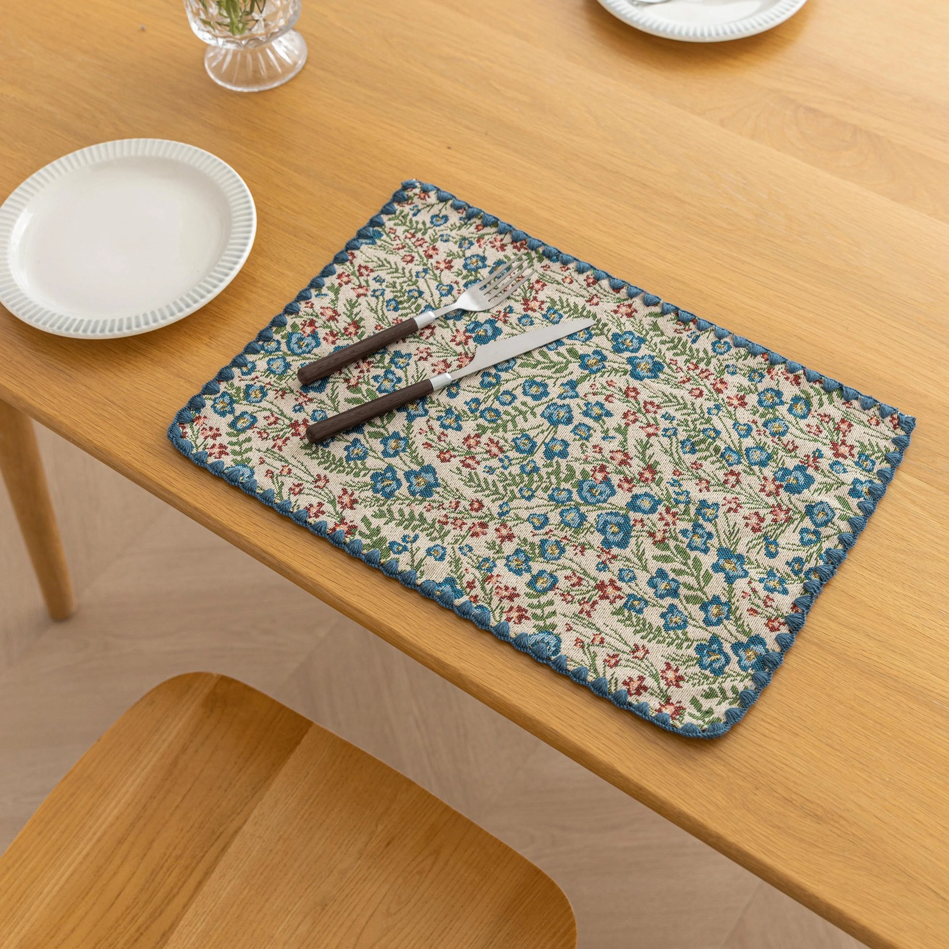 Charming floral woven placemat with blue and red blooms, perfect for adding a fresh, cottage-style touch to your dining table.