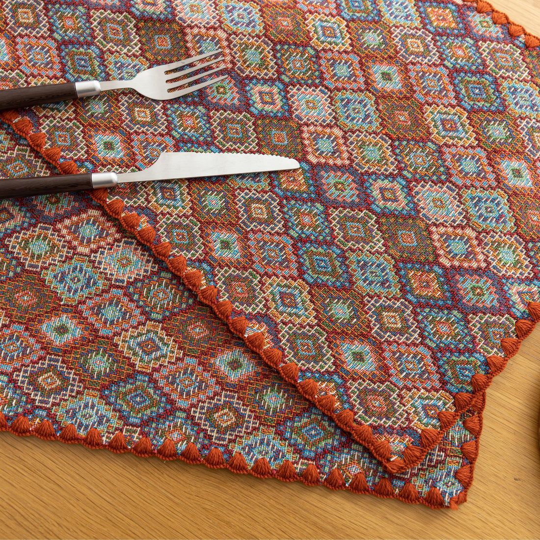 Colorful woven placemat with intricate diamond patterns, adding a vibrant boho touch while protecting your dining table.