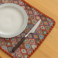 Colorful woven placemat with intricate diamond patterns, adding a vibrant boho touch while protecting your dining table.