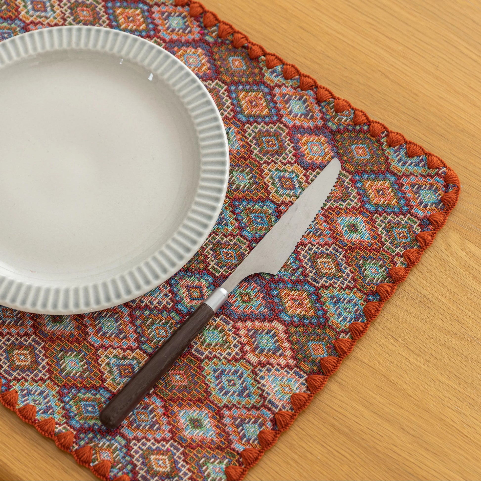 Colorful woven placemat with intricate diamond patterns, adding a vibrant boho touch while protecting your dining table.