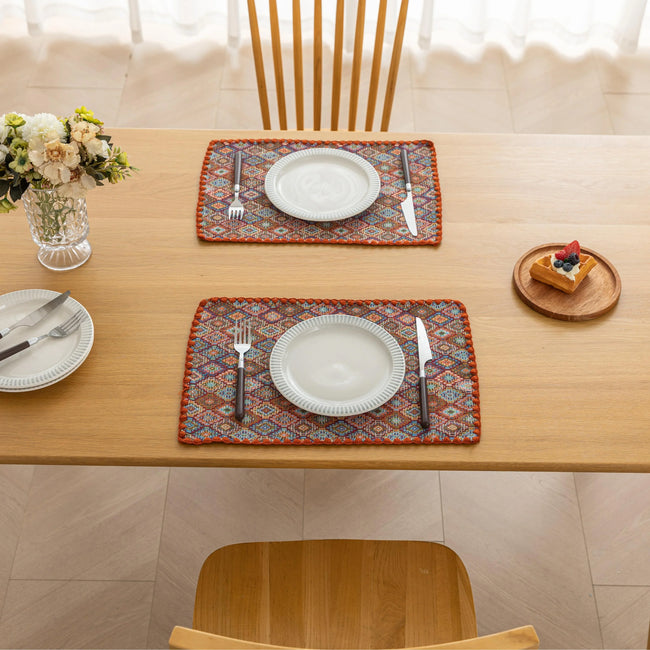 Colorful woven placemat with intricate diamond patterns, adding a vibrant boho touch while protecting your dining table.