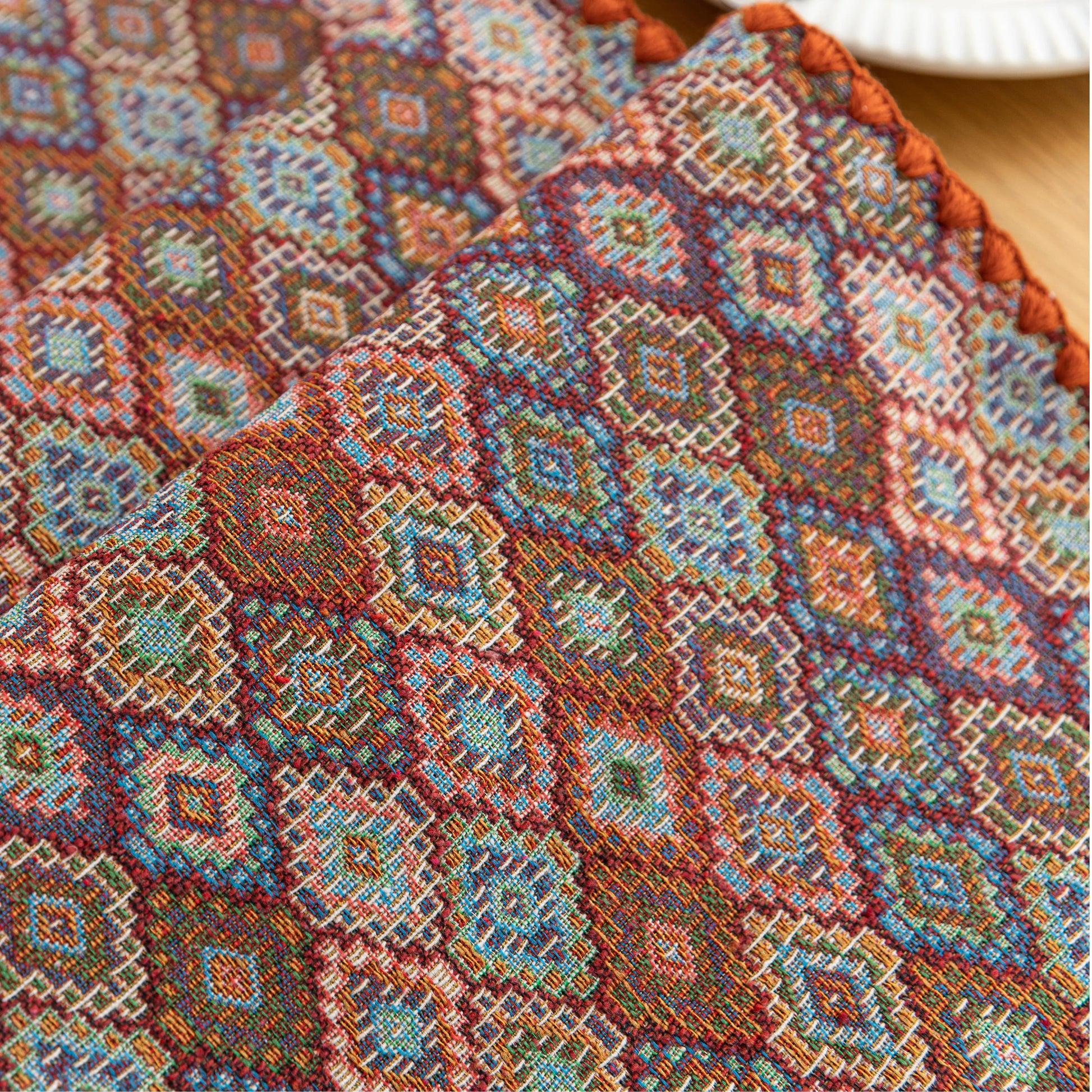 Colorful woven table runner with intricate diamond patterns, perfect for adding a vibrant boho touch to your dining or coffee table décor.