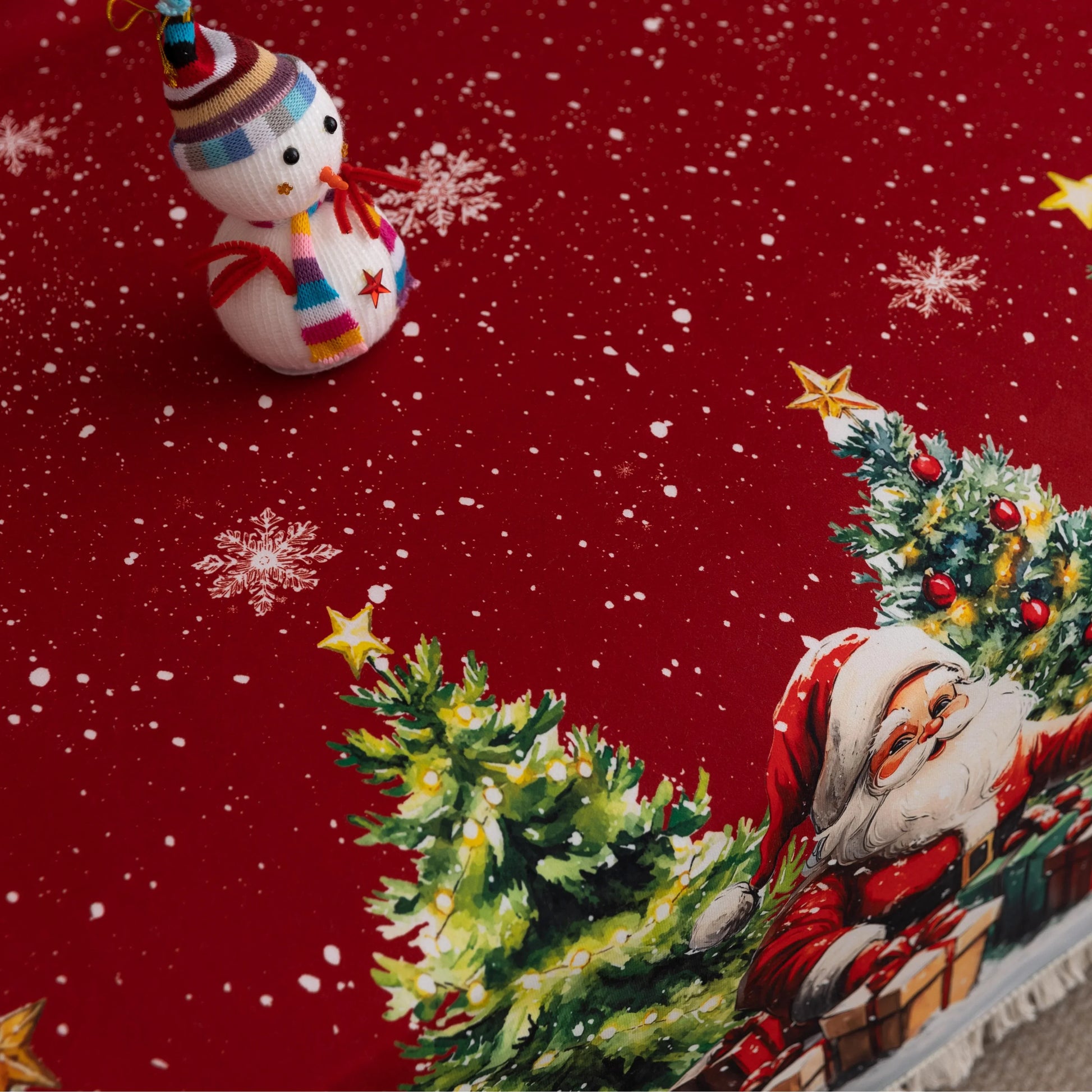 Festive red Christmas-themed sofa cover featuring decorated ornaments, snowflakes, snowy pine trees, a cheerful snowman, Santa Claus with gifts, and a cozy snow-covered house with poinsettias in the foreground.